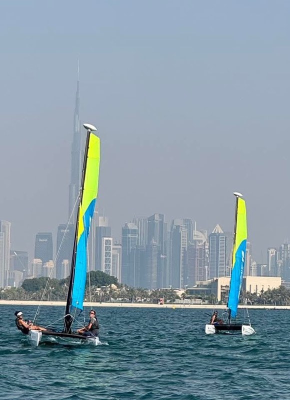 Two RS CAT 16 catamarans sailing on a hazy afternoon with the Burj Khalifa and the rest of the Dubai skyline standing behind the beach.